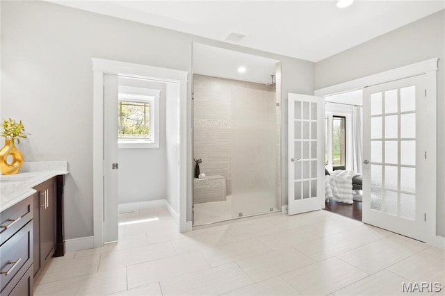 bathroom with french doors, tiled shower, baseboards, vanity, and recessed lighting
