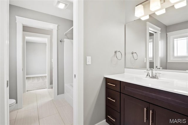 full bath with vanity, bathtub / shower combination, toilet, and baseboards