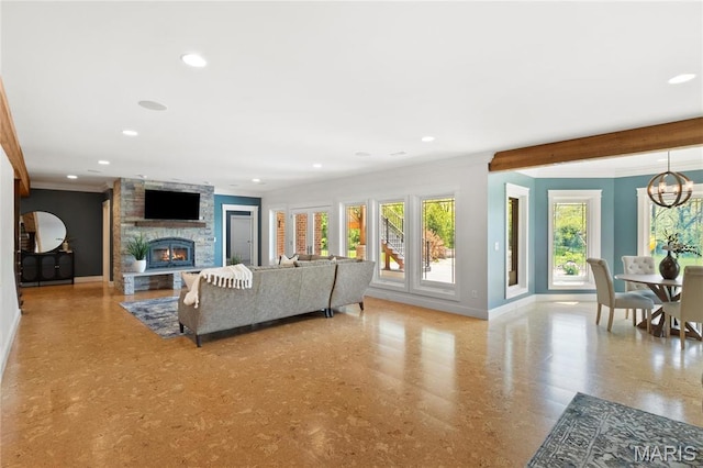 living room with baseboards, ornamental molding, a stone fireplace, recessed lighting, and a chandelier
