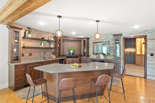 kitchen with a sink, light countertops, a kitchen breakfast bar, glass insert cabinets, and recessed lighting
