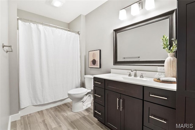 bathroom featuring toilet, vanity, wood finished floors, and shower / tub combo with curtain