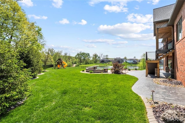 view of grassy yard featuring a playground and stairs