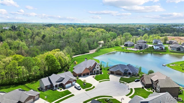 aerial perspective of suburban area featuring a nearby body of water and a heavily wooded area
