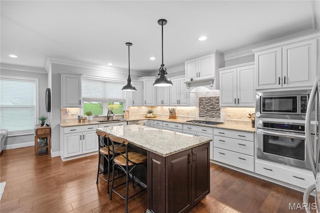 132 Hillary Cir, Wentzville, MO 63385 - kitchen with appliances with stainless steel finishes, a sink, crown molding, a center island, and a kitchen bar