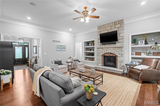 132 Hillary Cir, Wentzville, MO 63385 - living area featuring ornamental molding, built in shelves, a ceiling fan, a stone fireplace, and wood finished floors