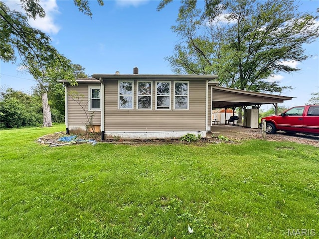 back of house with a chimney, a yard, and a carport