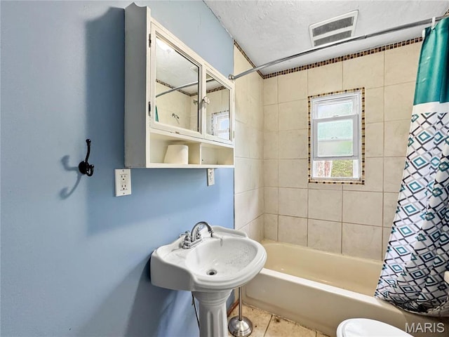 full bathroom featuring tile patterned flooring, shower / bath combo, toilet, and a textured ceiling