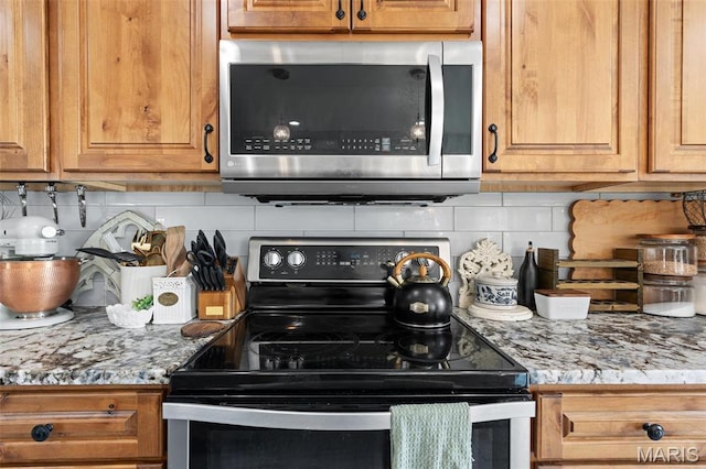 kitchen featuring stainless steel microwave, electric range, backsplash, and light countertops