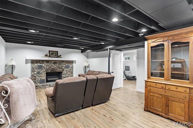 living room featuring light wood finished floors and a stone fireplace