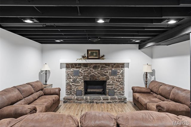 living room with wood finished floors and a stone fireplace