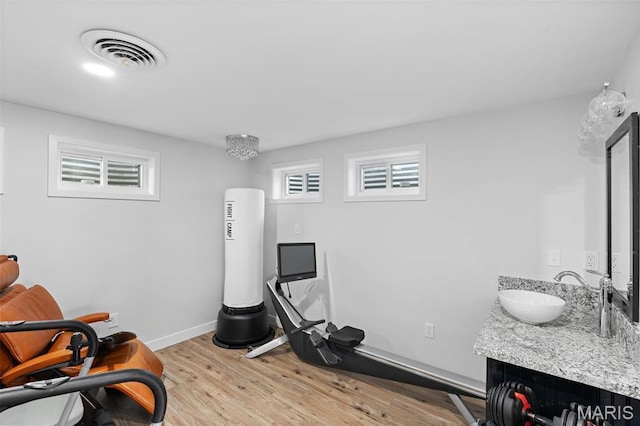 exercise area with a sink, light wood finished floors, and baseboards