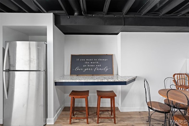 kitchen with freestanding refrigerator, wood finished floors, and baseboards