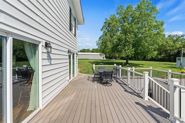 wooden terrace with outdoor dining space and a lawn