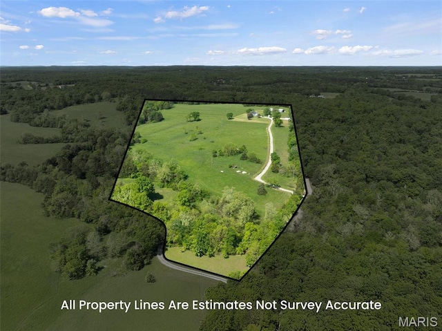 aerial view of property and surrounding area featuring a forest and property parcel outlined