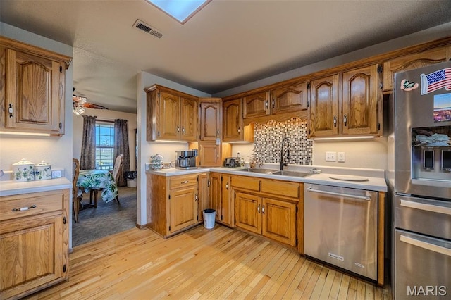 23598 Falcon Rd, Lebanon, MO 65536 - kitchen with stainless steel appliances, light wood finished floors, a sink, light countertops, and brown cabinetry