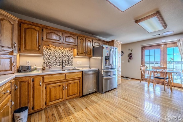 23598 Falcon Rd, Lebanon, MO 65536 - kitchen featuring stainless steel appliances, a sink, light countertops, brown cabinets, and light wood finished floors