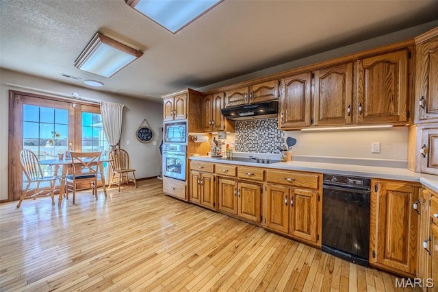 23598 Falcon Rd, Lebanon, MO 65536 - kitchen featuring appliances with stainless steel finishes, under cabinet range hood, light wood-type flooring, decorative backsplash, and light countertops
