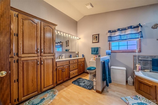 23598 Falcon Rd, Lebanon, MO 65536 - bathroom featuring wood finished floors, a bath, vanity, toilet, and lofted ceiling