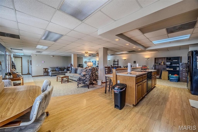 23598 Falcon Rd, Lebanon, MO 65536 - kitchen with light wood-style floors, a paneled ceiling, open floor plan, brown cabinetry, and a center island