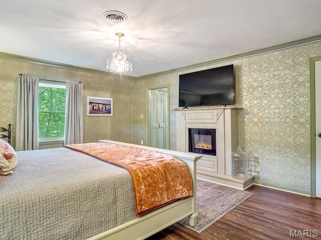 335 N Powder Mill Rd, Belleville, IL 62223 - bedroom with a chandelier, a glass covered fireplace, wood finished floors, ornamental molding, and wallpapered walls