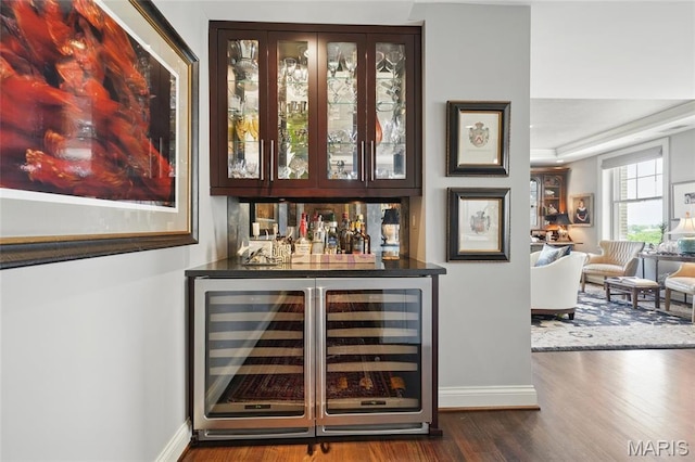 indoor dry bar featuring wine cooler, baseboards, and dark wood finished floors