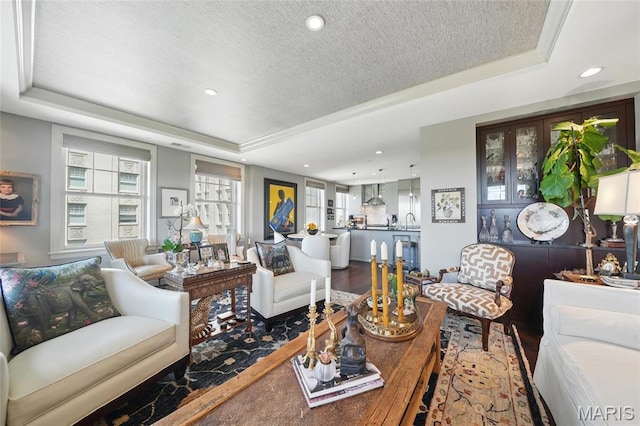 living area with a tray ceiling, wood finished floors, recessed lighting, and a textured ceiling