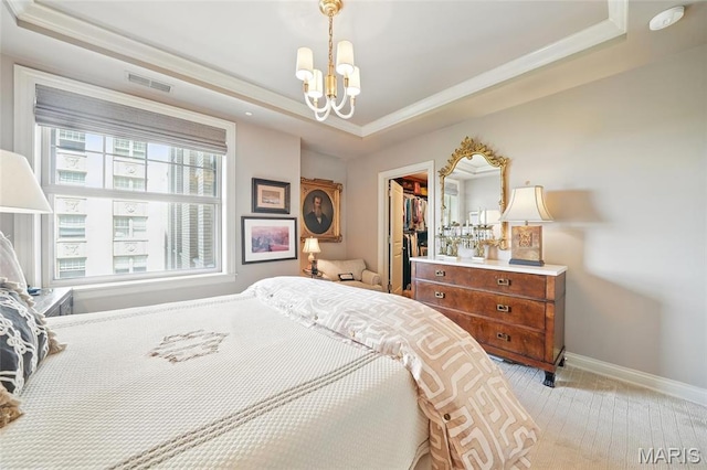 bedroom featuring a tray ceiling, a chandelier, a spacious closet, ornamental molding, and baseboards