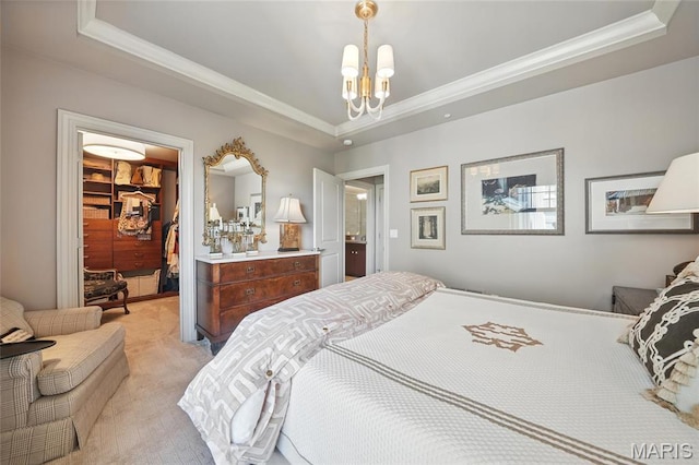bedroom with a tray ceiling, crown molding, light carpet, a chandelier, and a walk in closet