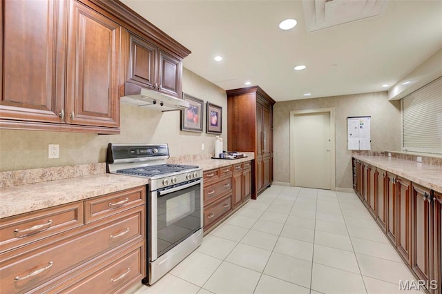 kitchen with stainless steel gas range, under cabinet range hood, recessed lighting, light tile patterned floors, and light stone countertops