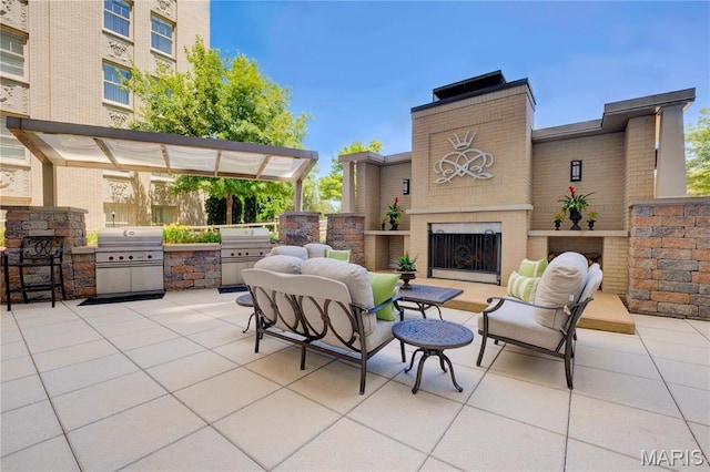 view of patio with an outdoor brick fireplace, an outdoor kitchen, and grilling area