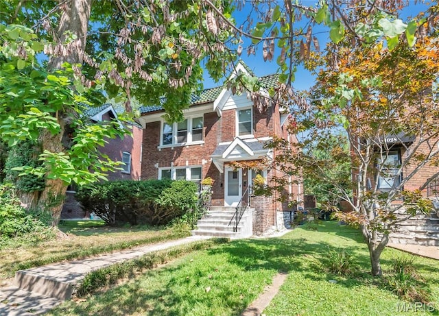 view of front facade featuring brick siding, a front lawn, and a tiled roof