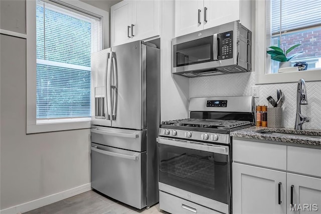 kitchen with appliances with stainless steel finishes, tasteful backsplash, and healthy amount of natural light