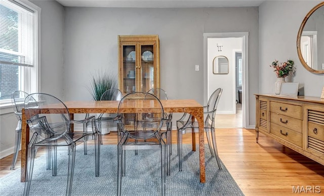 dining space featuring light wood finished floors and baseboards