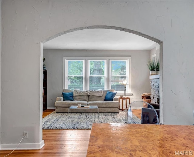 living room with arched walkways, wood finished floors, and baseboards