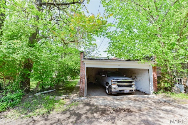 garage featuring asphalt driveway and a carport
