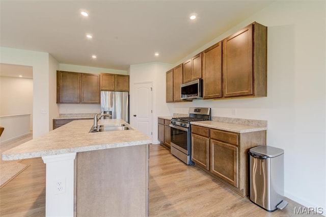 kitchen with appliances with stainless steel finishes, a sink, light wood-style flooring, recessed lighting, and light countertops