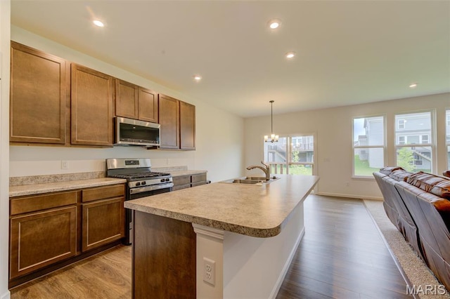 kitchen featuring appliances with stainless steel finishes, a sink, dark wood finished floors, hanging light fixtures, and open floor plan