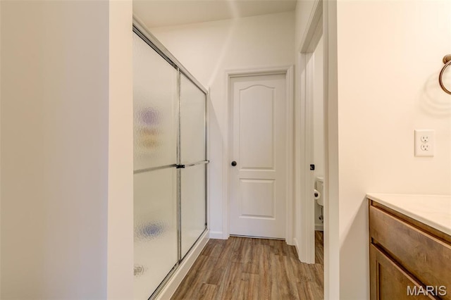 full bath featuring wood finished floors, a stall shower, toilet, and vanity