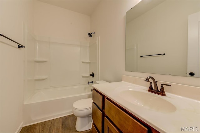 bathroom with toilet, wood finished floors, vanity, and  shower combination