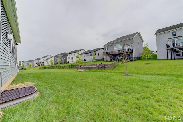 view of green lawn with a residential view, stairs, and a deck