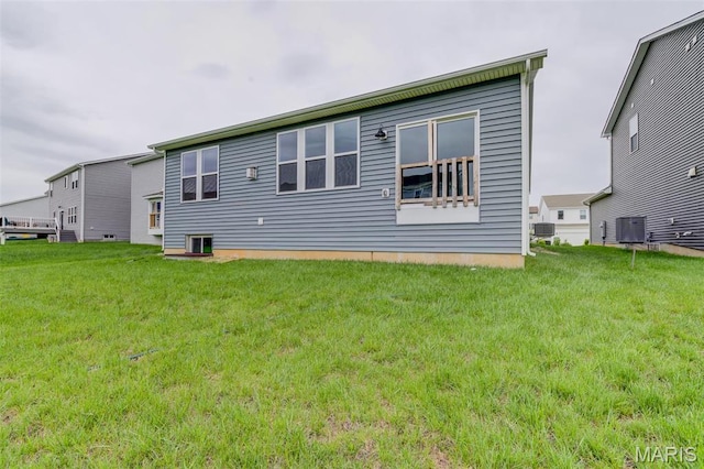 rear view of house with central AC unit and a yard