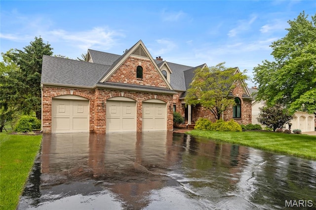 view of front of property with a garage, a front yard, driveway, and a shingled roof