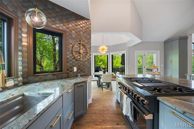 kitchen with range with two ovens, light stone countertops, dark wood-style floors, pendant lighting, and gray cabinetry