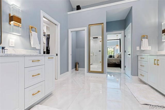 ensuite bathroom featuring marble finish floors, baseboards, vanity, and a stall shower