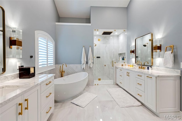 full bathroom featuring a stall shower, a freestanding tub, two vanities, a high ceiling, and marble finish floors