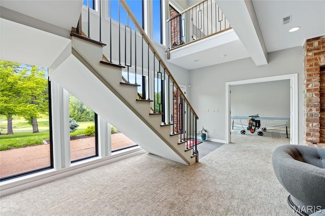 stairway featuring carpet, baseboards, and a high ceiling