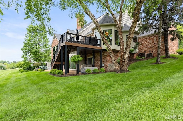 rear view of house with a deck, brick siding, stairway, and a yard