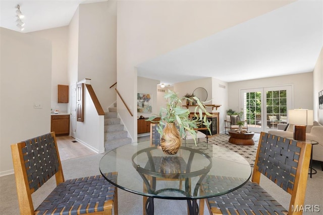 8704 Garden Ct, Brentwood, MO 63144 - dining space with stairs, rail lighting, light colored carpet, and a towering ceiling
