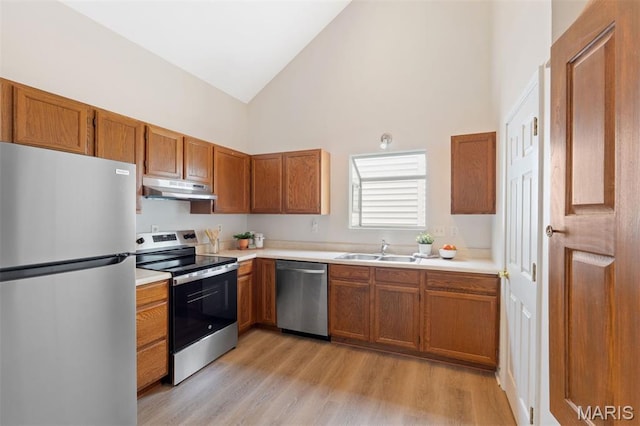 8704 Garden Ct, Brentwood, MO 63144 - kitchen with appliances with stainless steel finishes, under cabinet range hood, high vaulted ceiling, light wood finished floors, and light countertops