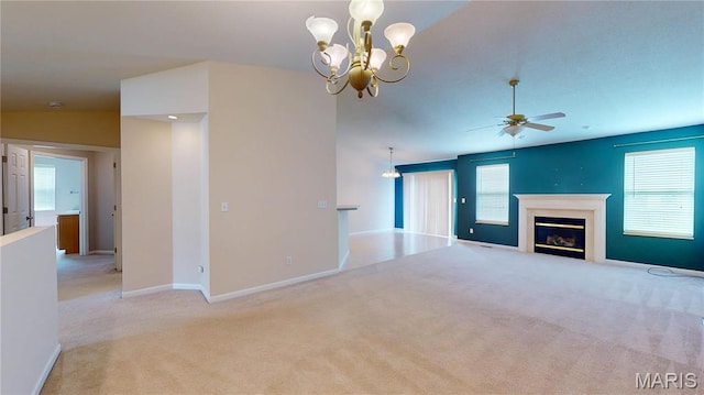 unfurnished living room featuring a ceiling fan, carpet, a glass covered fireplace, baseboards, and a chandelier